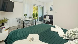 A modern hotel room with a bed, a desk, a chair, and a TV. - Studio in Niechorze Near Baltic Beach (Rewal)