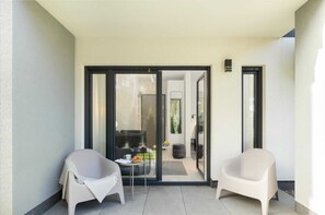 A modern, minimalist balcony with two white chairs, a small table, and a glass door leading to an interior space. - Studio in Niechorze Near Baltic Beach (Rewal)