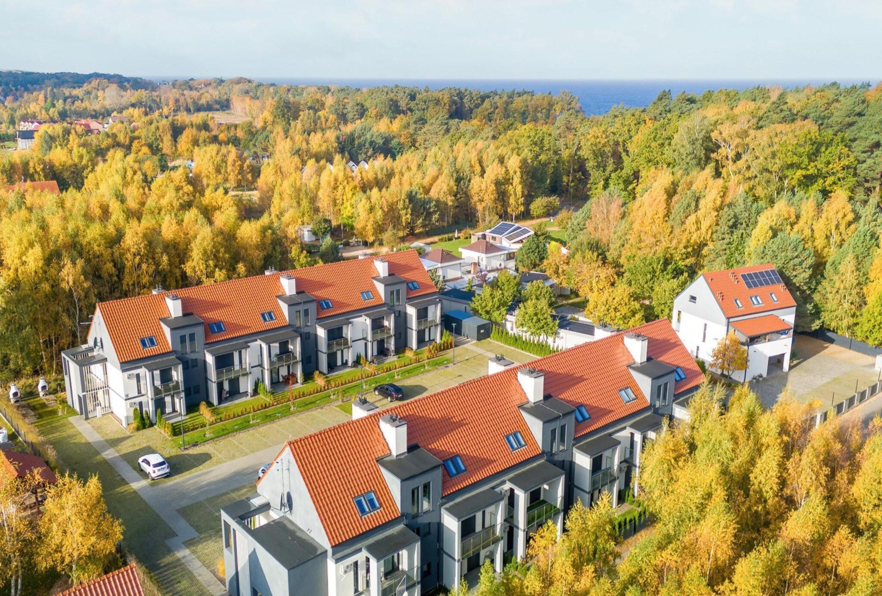 Un moderno complejo residencial con varias edificaciones, techos de tejas rojas y paneles solares.