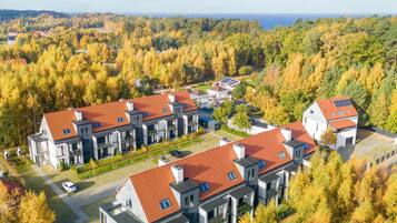 Un moderno complejo residencial con varias edificaciones, techos de tejas rojas y paneles solares.