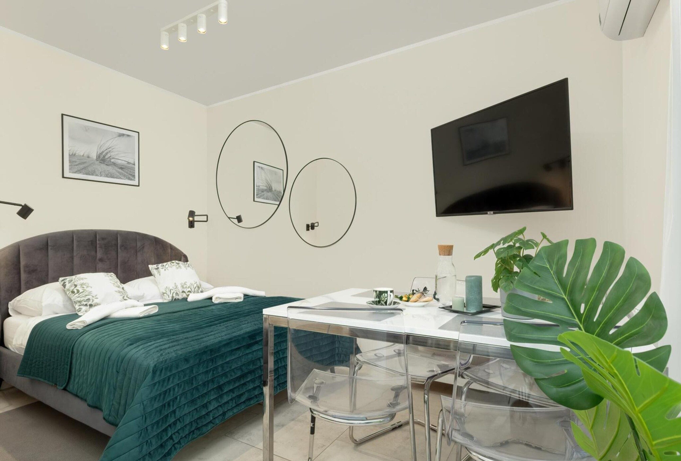A modern hotel room with a bed, a desk, and a TV.
