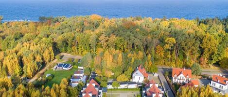 An aerial view of a residential area with houses, a parking lot, and a body of water in the background.