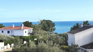Zona residencial a la costa, amb cases blanques, un cel blau clar i el mar al fons.