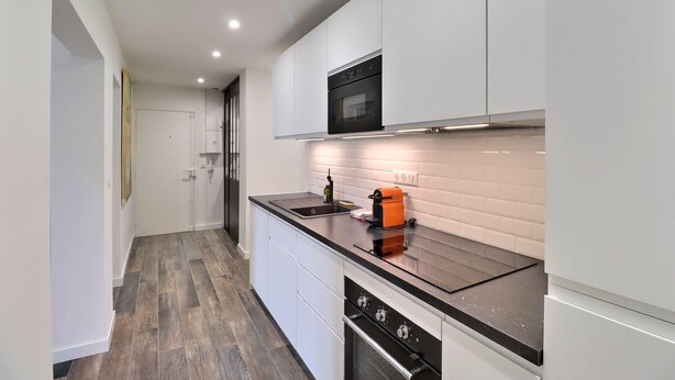 A modern kitchen with white cabinets, a black countertop, and a built-in oven. - The Aixoise Escape - Close to the city center (Aix-en-Provence)