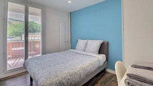 A bedroom with a bed, a blue wall, and a sliding glass door to the balcony. - The Aixoise Escape - Close to the city center (Aix-en-Provence)