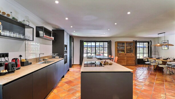 Una cocina moderna con una isla central, electrodomésticos integrados y una zona de comedor con mesa y sillas.
