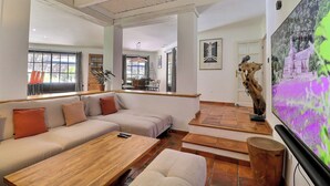 Amplia sala de estar con un sofá grande, una mesa de centro de madera y un televisor de pantalla plana montado en la pared.