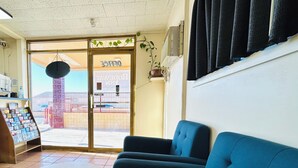 Una hall con una reception, un divano blu, un tavolino e vista sull'esterno.