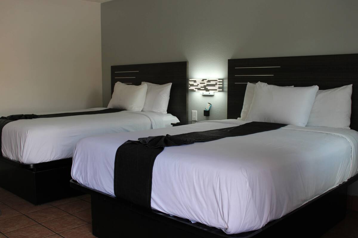 Two single beds with black headboards and white bedding in a hotel room.