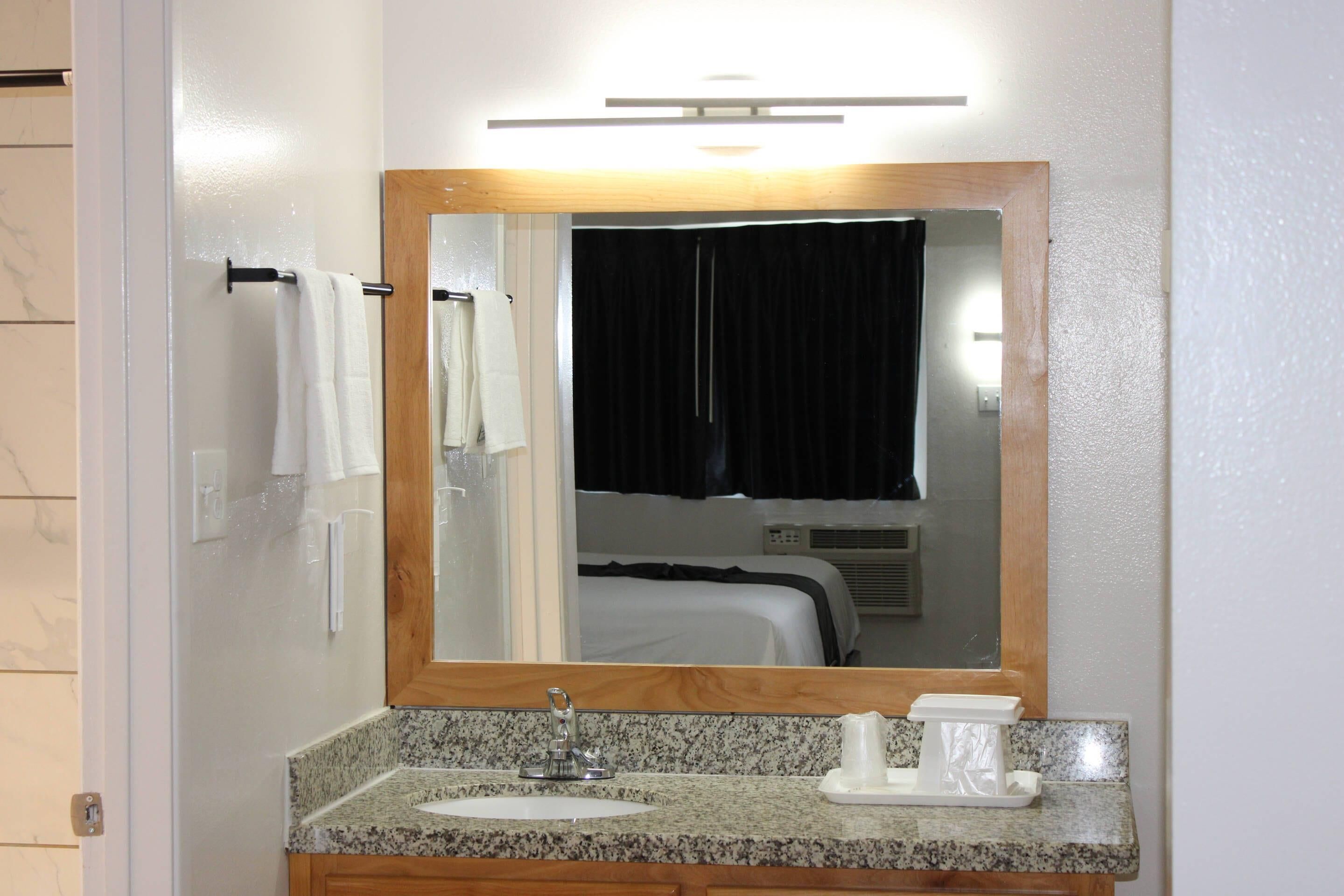 A bathroom with a granite countertop, a sink, a mirror, and a towel rack.