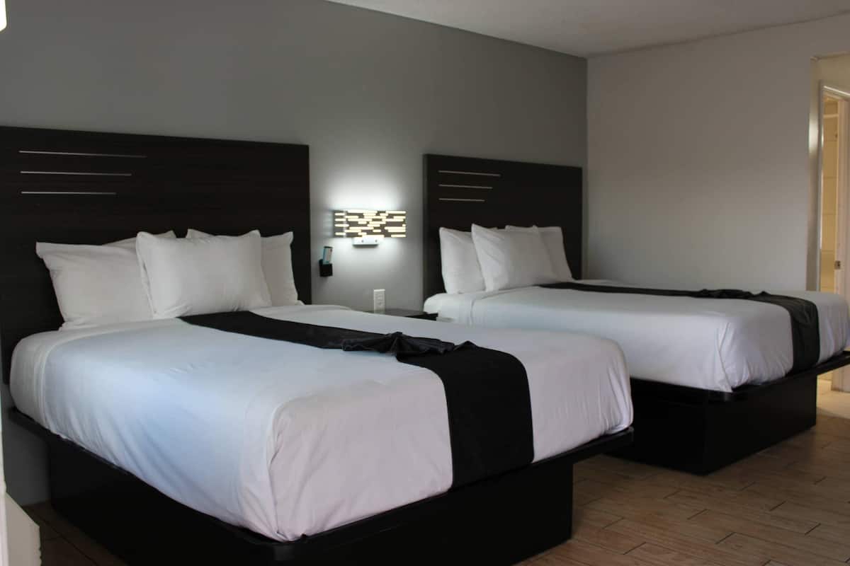 A hotel room with two beds, each with white bedding and black headboards.