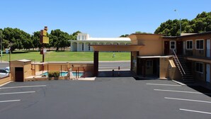 Un motel con piscina, un'area di parcheggio recintata e un edificio con un balcone sullo sfondo.
