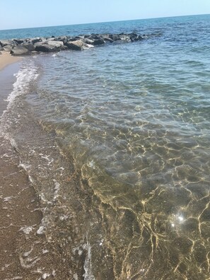 Une plage avec une eau claire, des rochers et une rive sablonneuse.