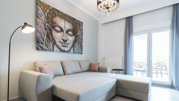 Ein modernes Wohnzimmer mit einem Ecksofa, einer Stehlampe und einem großen Buddha-Gemälde an der Wand.