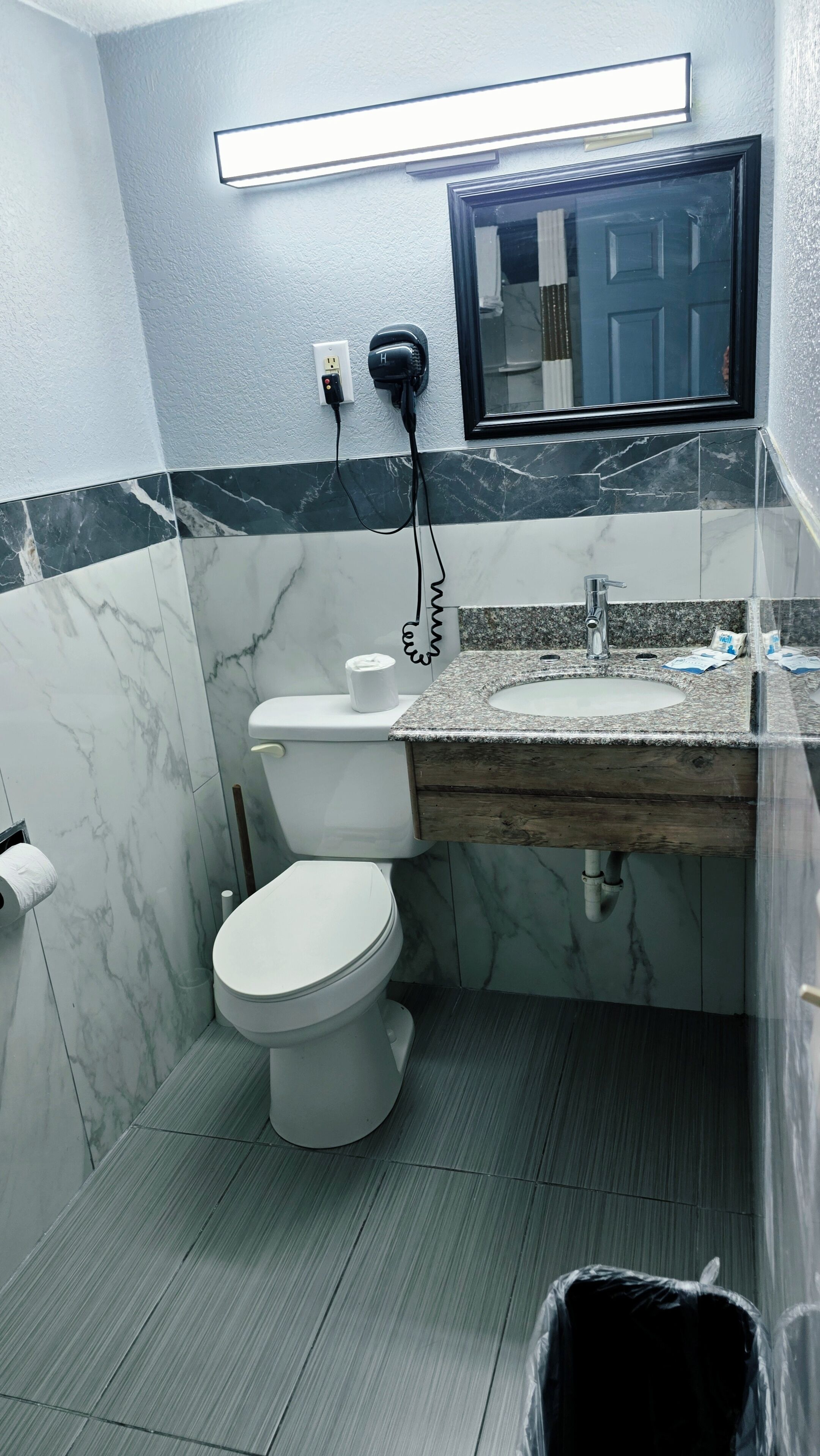 Une salle de bain avec des toilettes, un lavabo et un miroir.