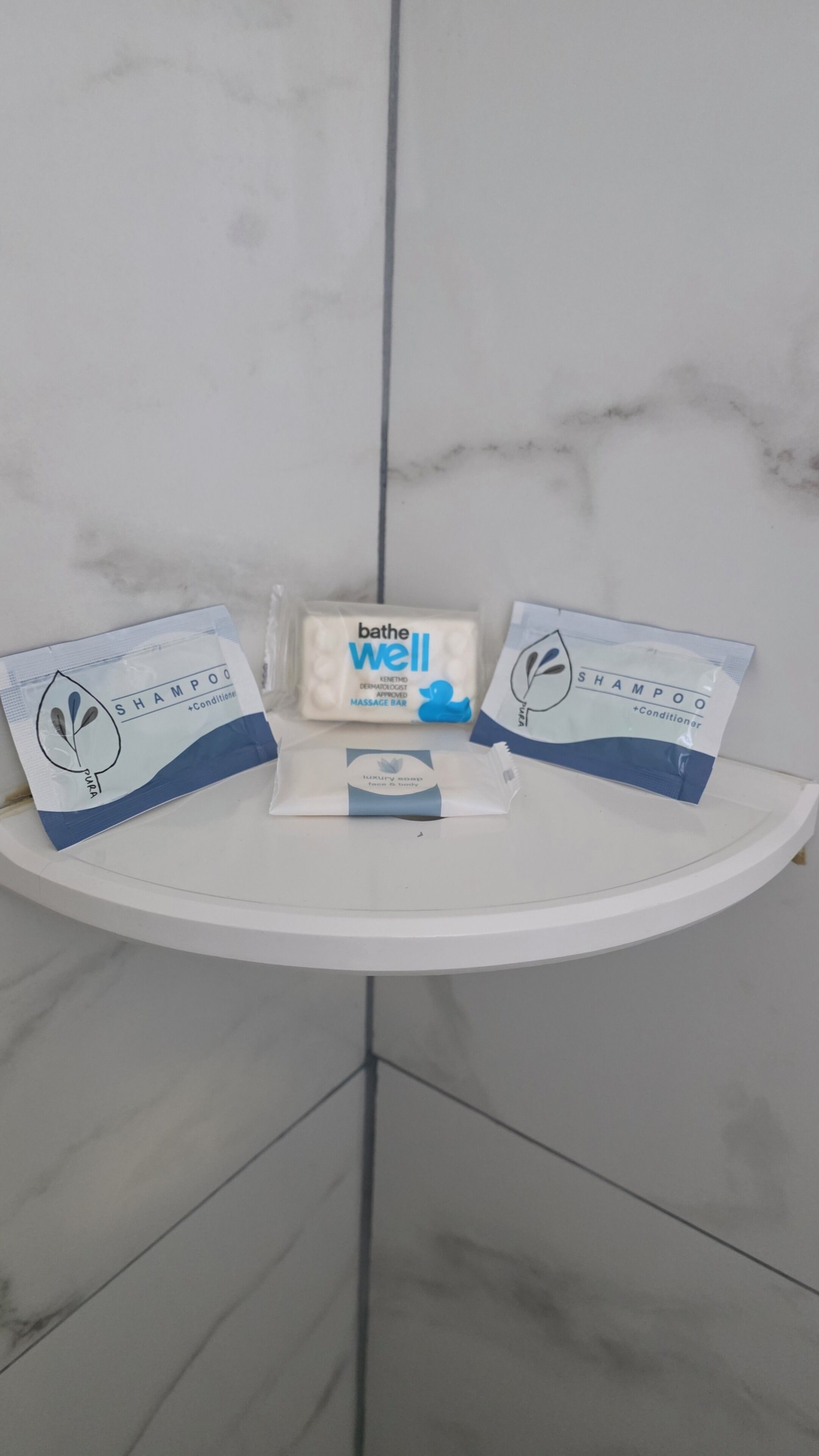 Un baño con un lavabo blanco, una barra de champú de baño y cuerpo, y dos botellas de acondicionador.