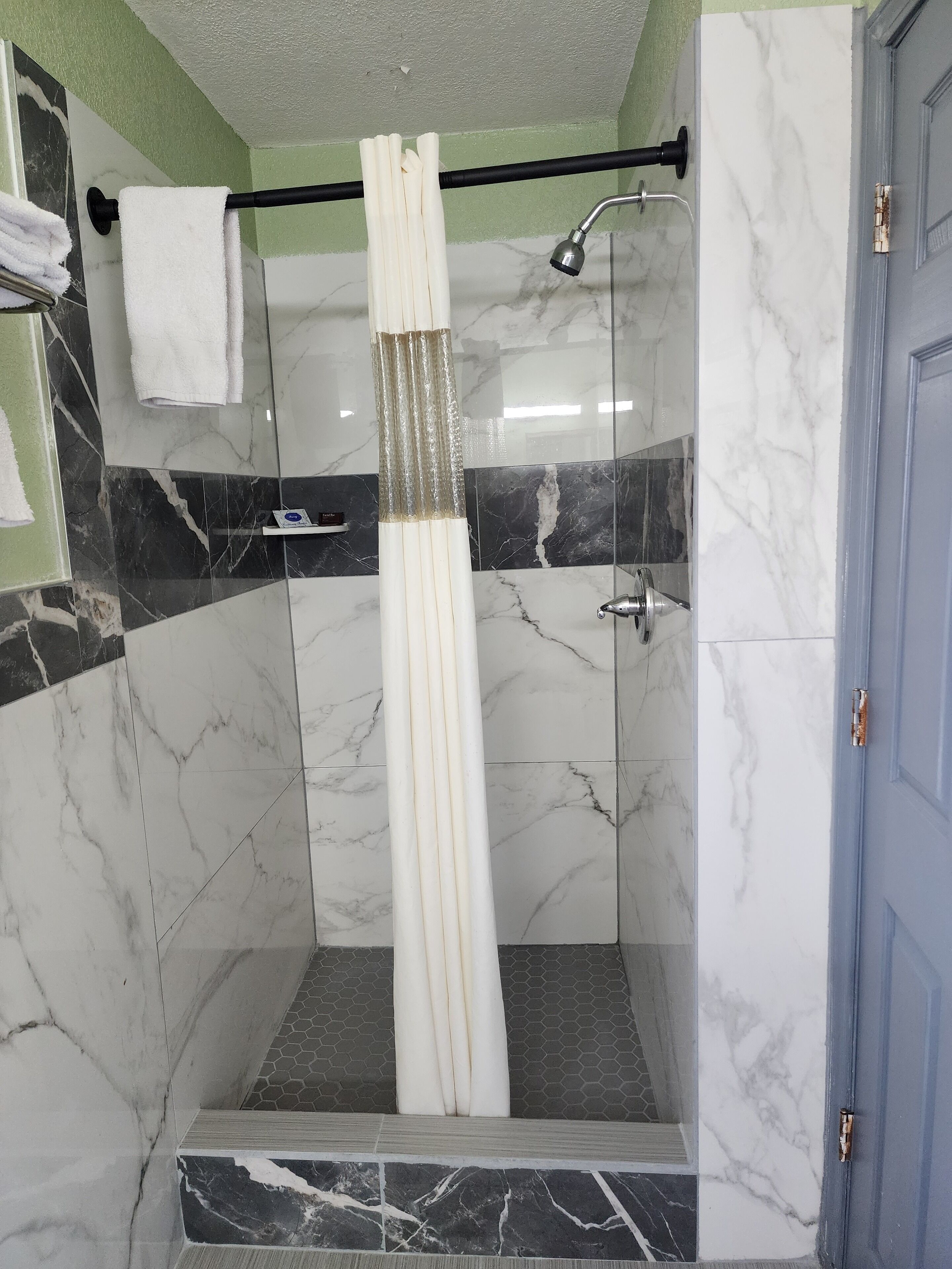 A shower area with a glass door, a towel rack with a white towel, and a showerhead.