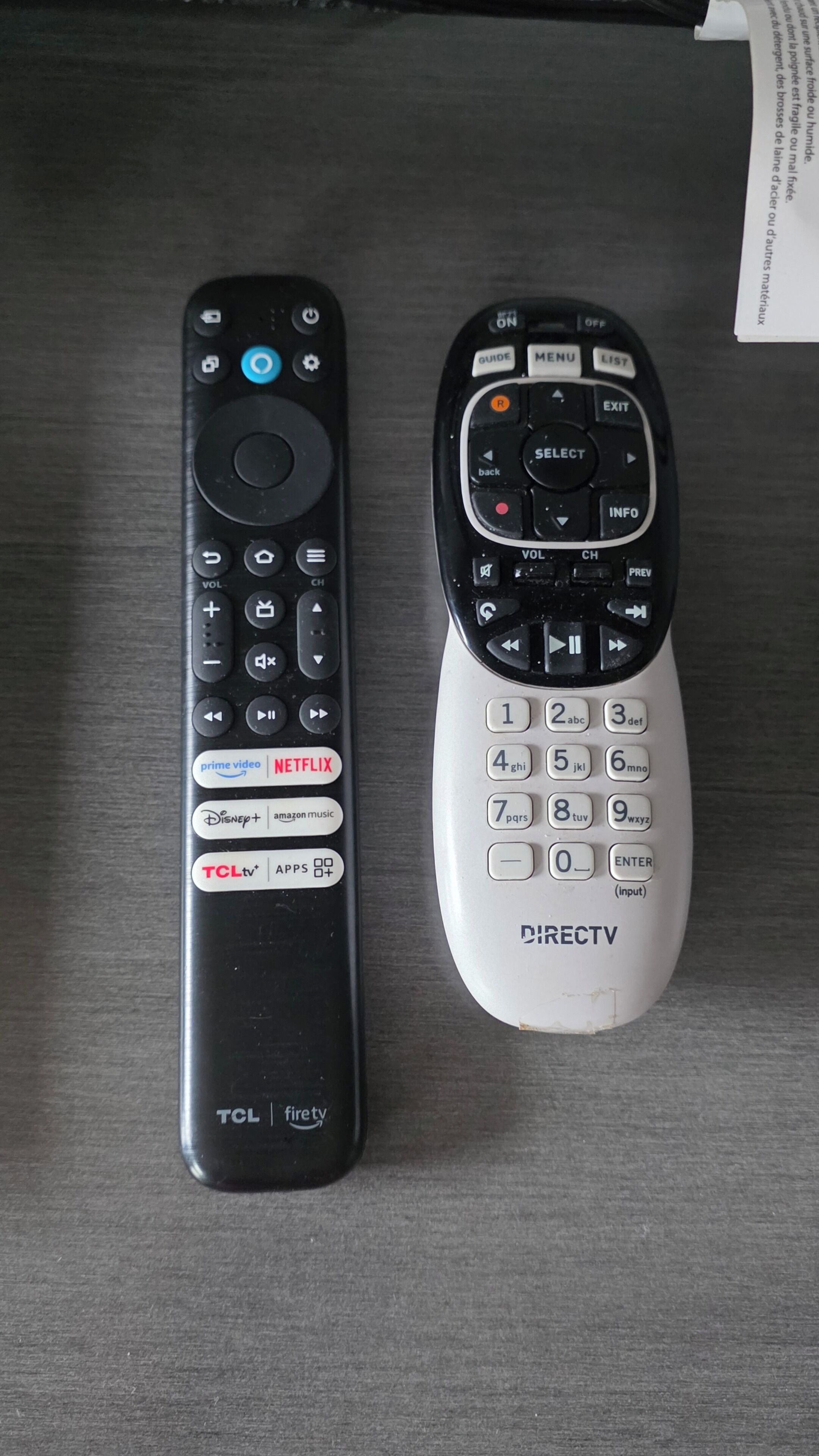 Deux télécommandes, une noire et une blanche, posées sur une surface en bois.