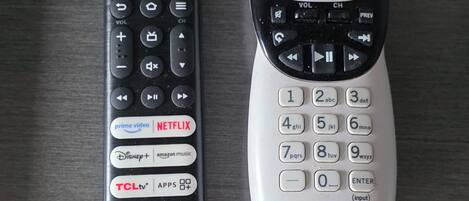 Deux télécommandes, une noire et une blanche, posées sur une surface en bois.