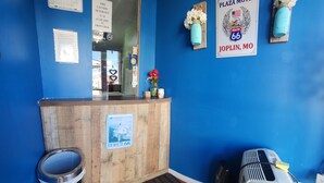A motel reception desk with a blue wall, a wooden counter, a trash can, and a heater. - Plaza Motel (Joplin)