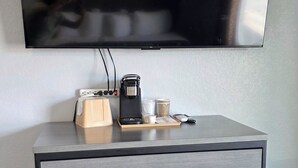 A modern living space with a flat-screen TV labeled 'SMART TV,' a coffee maker, and a wooden tray with various items. - Plaza Motel (Joplin)