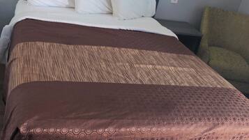 Une chambre d’hôtel avec un lit, une tête de lit, une table de chevet et une chaise.