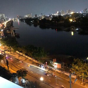 A nighttime cityscape with a river, illuminated buildings, and a bridge. - Bao Aurora Oasis Hotel (Ho Chi Minh City)