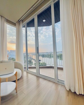 A modern living room with a large sliding glass door leading to a balcony with a city view. - Bao Aurora Oasis Hotel (Ho Chi Minh City)