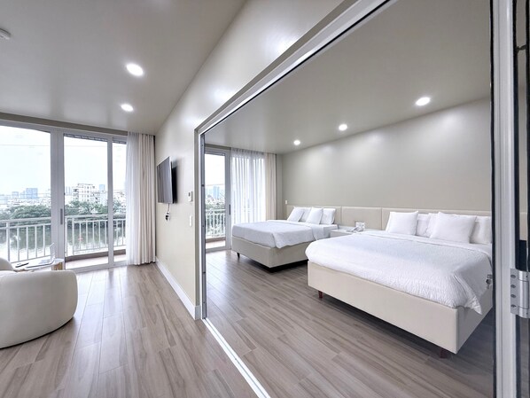 Una habitación de hotel moderna con dos camas, un televisor y un balcón con vista a la ciudad.