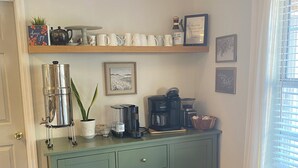 A kitchen with a teal cabinet, a coffee maker, and a dining table.
