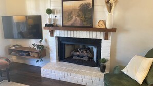 A living room with a fireplace, a mounted TV, and a green couch.