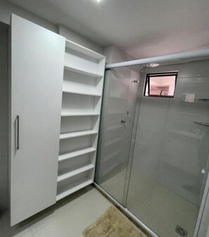 A room with a large white wardrobe, a glass shower enclosure, and a small window. - Melhores Flats - Fantástica localização (João Pessoa)