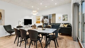 A modern dining area with a white table, black chairs, and a central vase with flowers.