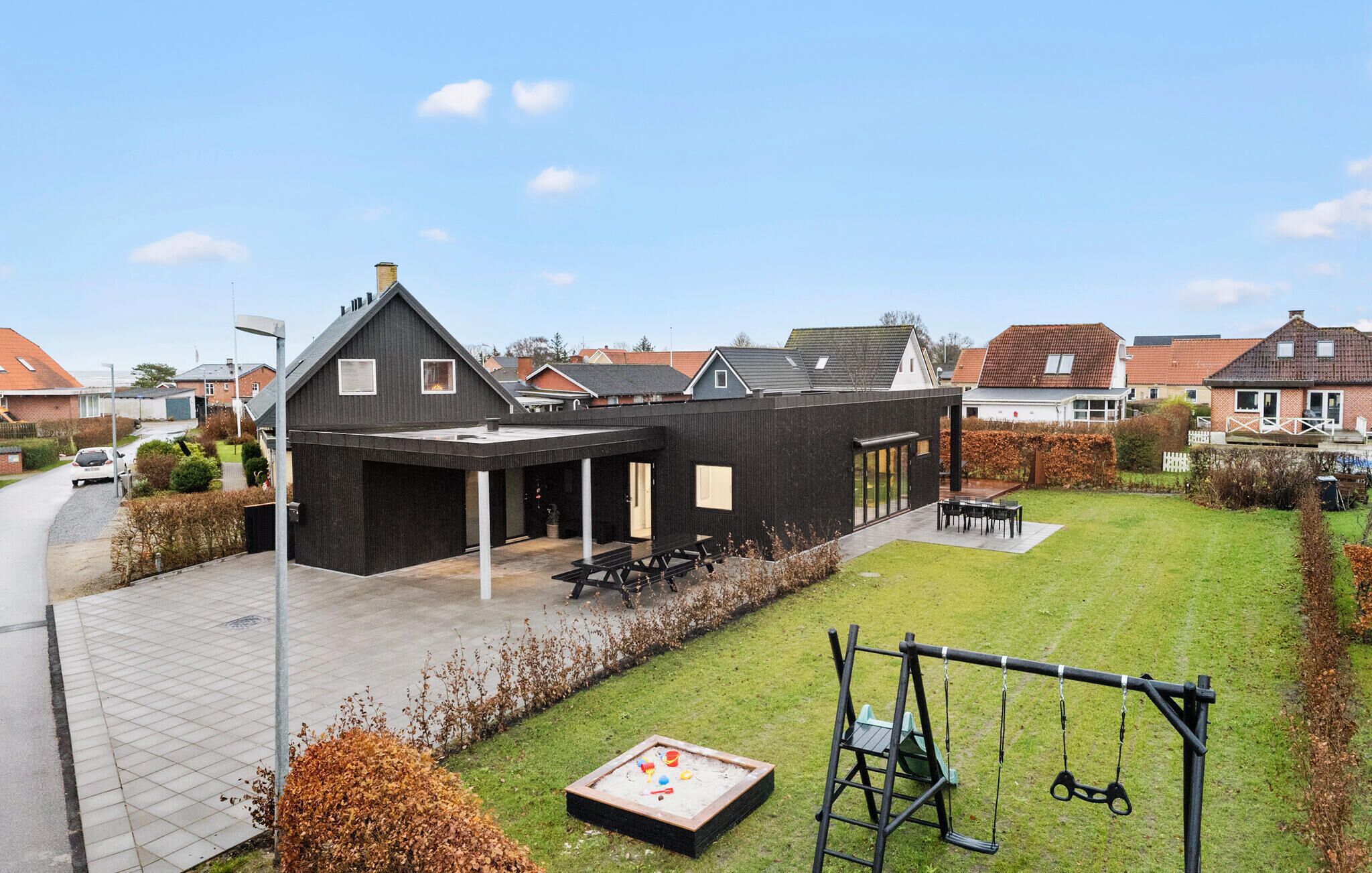 A modern building with a covered patio area, a swing set, and a small play area with toys.