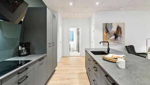 A modern kitchen with a built-in oven, a coffee machine, and a large island with a sink.