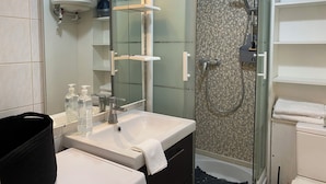 A modern bathroom with a glass-enclosed shower, a sink with a mirror, and a toilet. - Cosy studio in Évreux - Ideal! (Évreux)