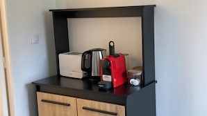 A kitchenette with a toaster, a coffee maker, and a container on a black countertop. - Cosy studio in Évreux - Ideal! (Évreux)