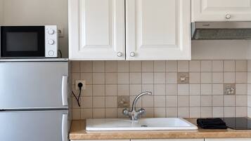 A kitchen with white cabinets, a microwave, a sink, and a stove.