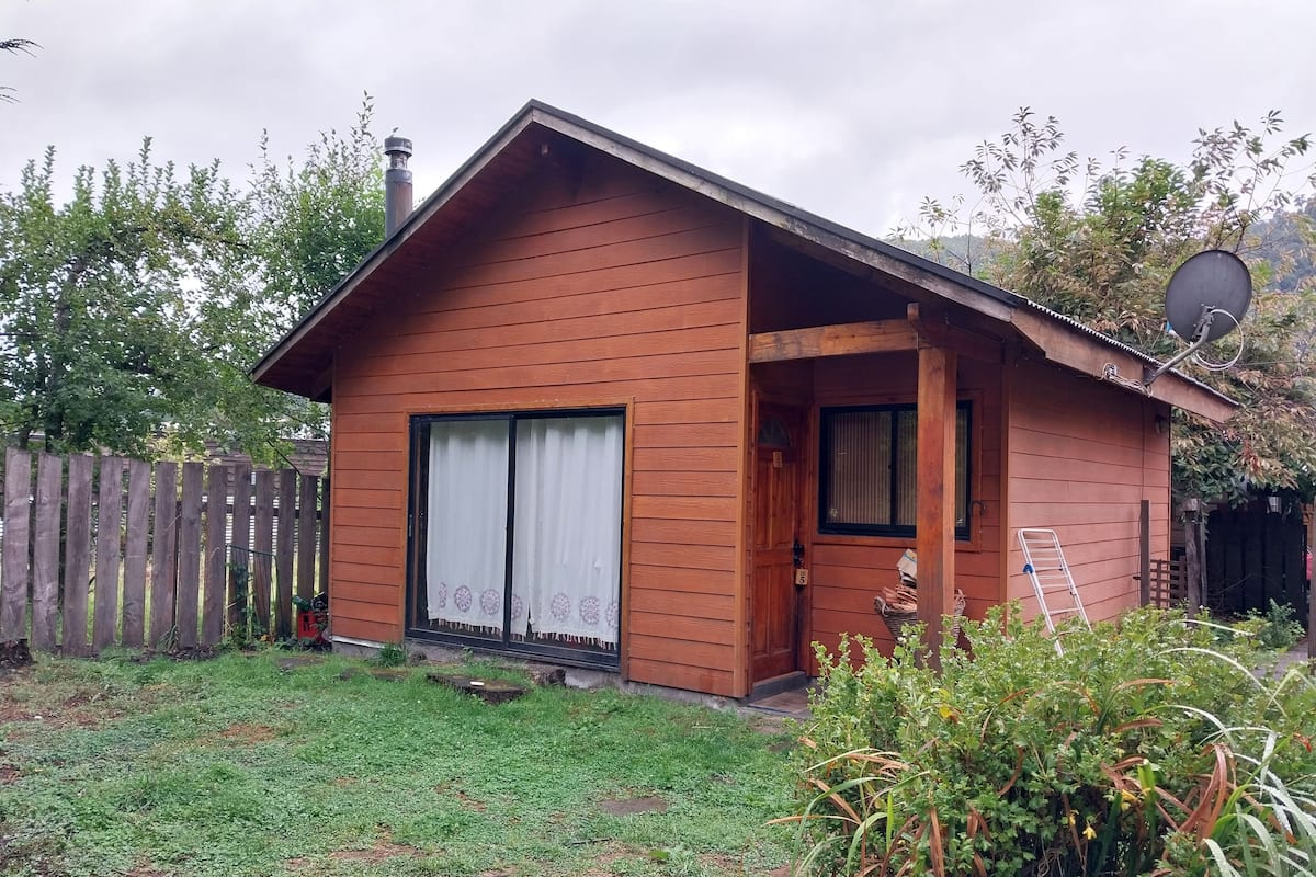 Ein Holzhaus mit geneigtem Dach, einer Haustür und einer kleinen Veranda.