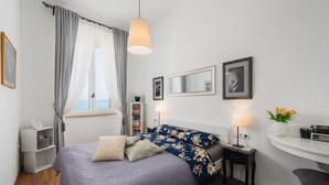 Un dormitorio con cama, mesita de noche, lámpara, escritorio y silla.