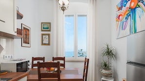 Una cocina moderna con muebles de madera, una mesa de comedor y vistas al mar a través de amplios ventanales.