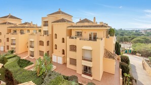 A multi-story residential building with balconies, a courtyard, and a view of the surrounding greenery. - Charming Villa With Terrace (Marbella)