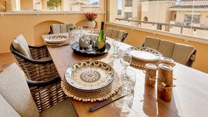 A dining table set with plates, glasses, and a bottle, with a view of buildings through the window. - Charming Villa With Terrace (Marbella)