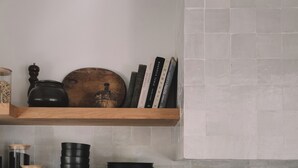 Una cocina con encimera negra, estufa y estantes con utensilios de cocina.