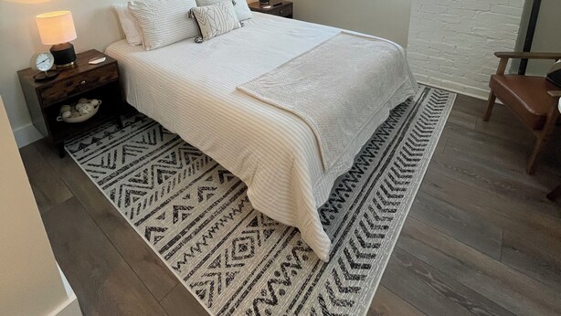 A bedroom with a bed, nightstands, wall art, a window, and a chair. - The Innwoods - Studio Apartment 1 (Tannersville)