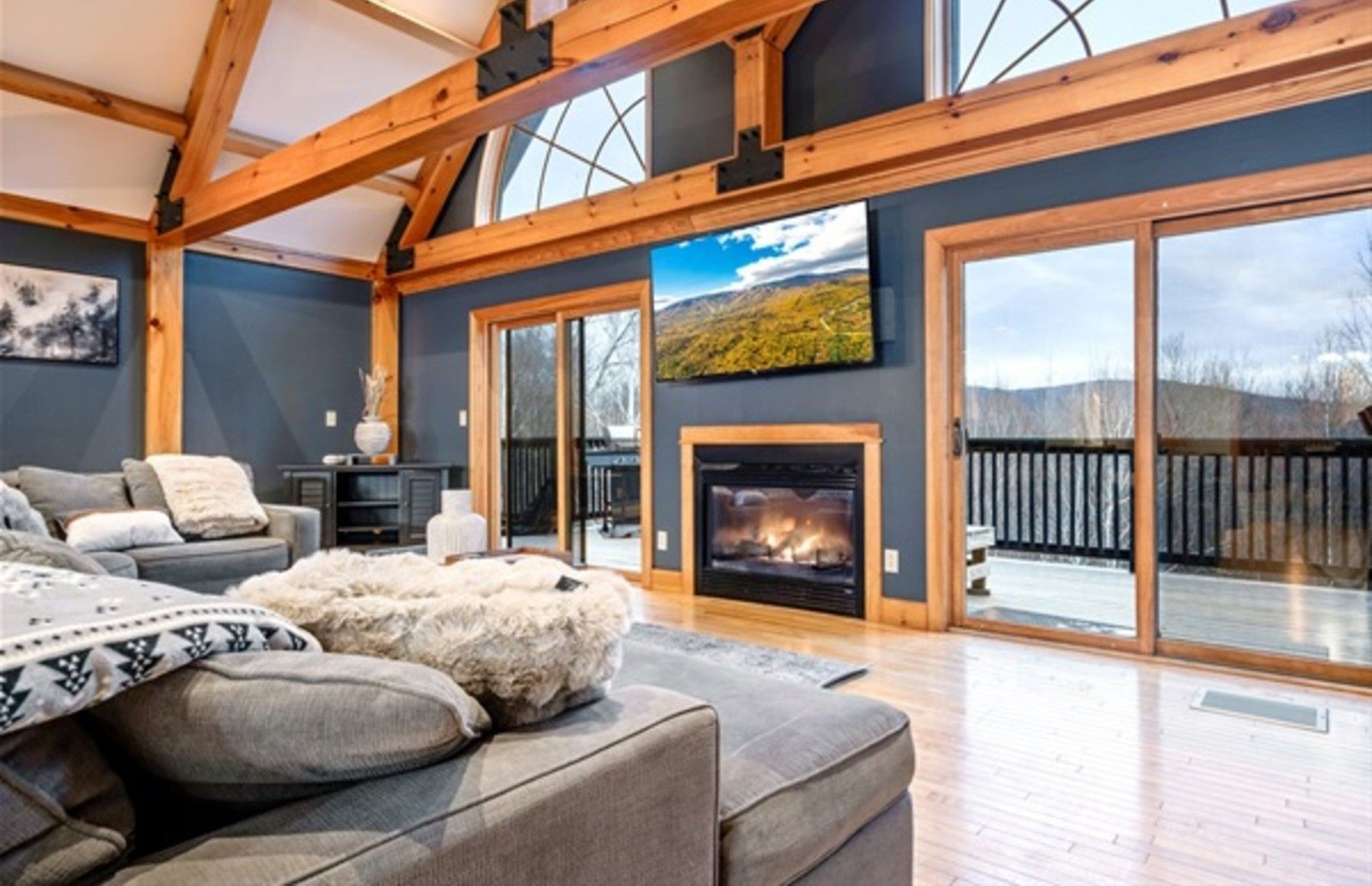 A spacious living room with a fireplace, large windows, and a view of the outdoors.