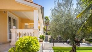 A yellow building with a white balcony, a green lawn, and a tree with dense foliage. - Apartment in Porec Near the Sea and Beaches (Porec)
