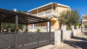 A two-story house with a balcony, a covered outdoor area, and a gated entrance. - Apartment in Porec Near the Sea and Beaches (Porec)