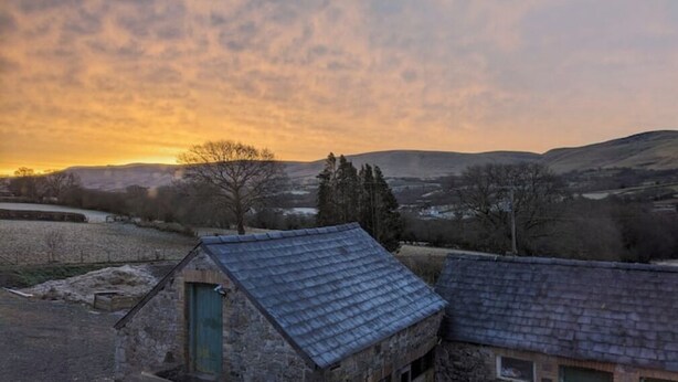 A rural landscape with a stone building featuring a sloped roof and a small door. - Shepherds Hut in Dark Sky Reserve

 (Gwynfe)