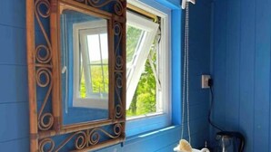 A bathroom with a wooden ceiling, a large window with a white blind, a sink with a faucet, and a bottle of hand soap. - Shepherds Hut in Dark Sky Reserve

 (Gwynfe)